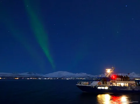 Nordlys over fjorden set fra Tromsøs nordlyskrydstogtbåd