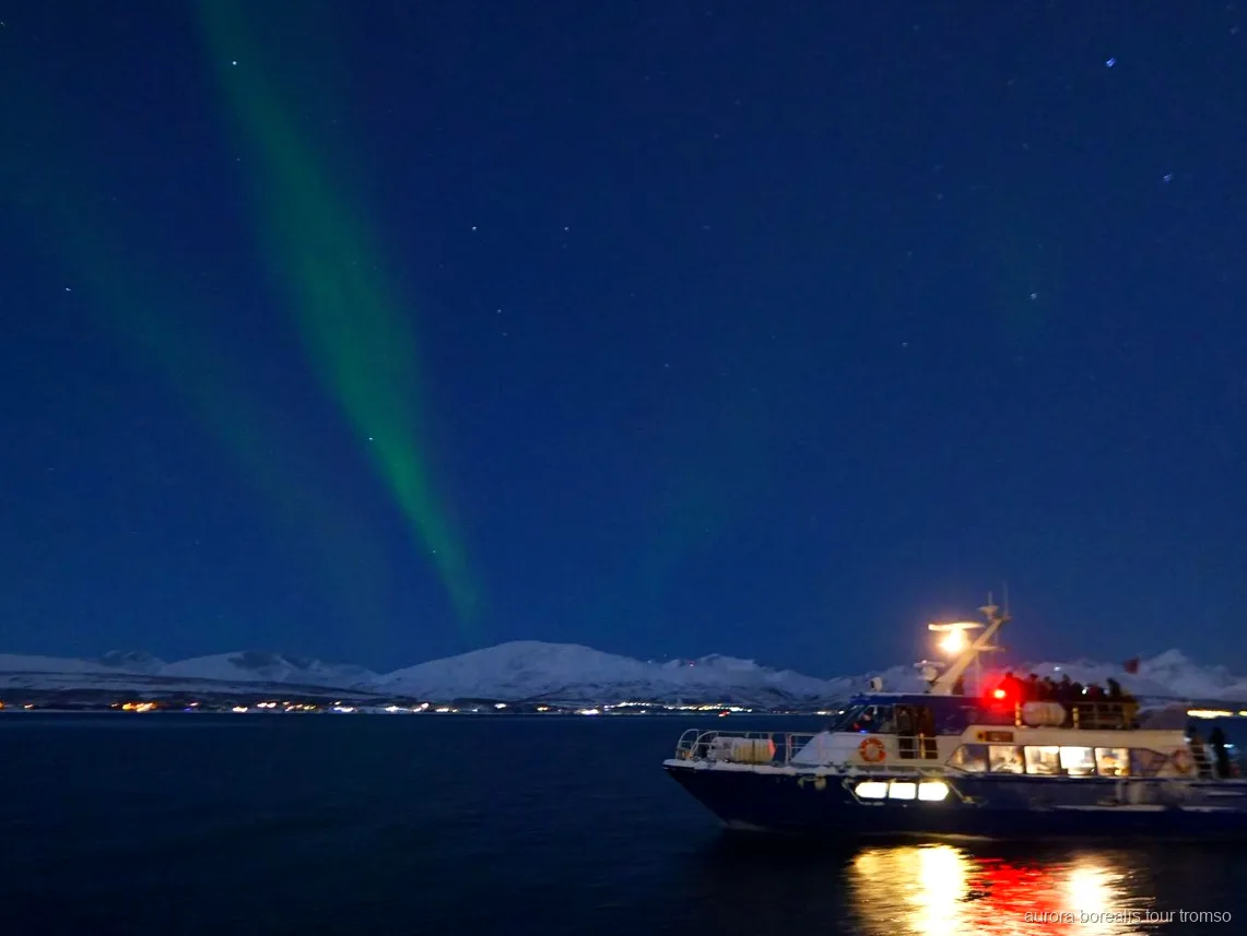 Aurora boreale sul fiordo vista dalla barca della crociera per l'aurora boreale di Tromsø