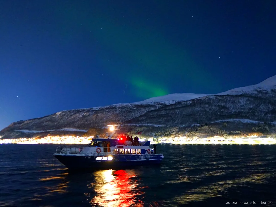 Tripulante a ajudar um convidado a configurar a câmara no cruzeiro de aurora boreal de Tromso
