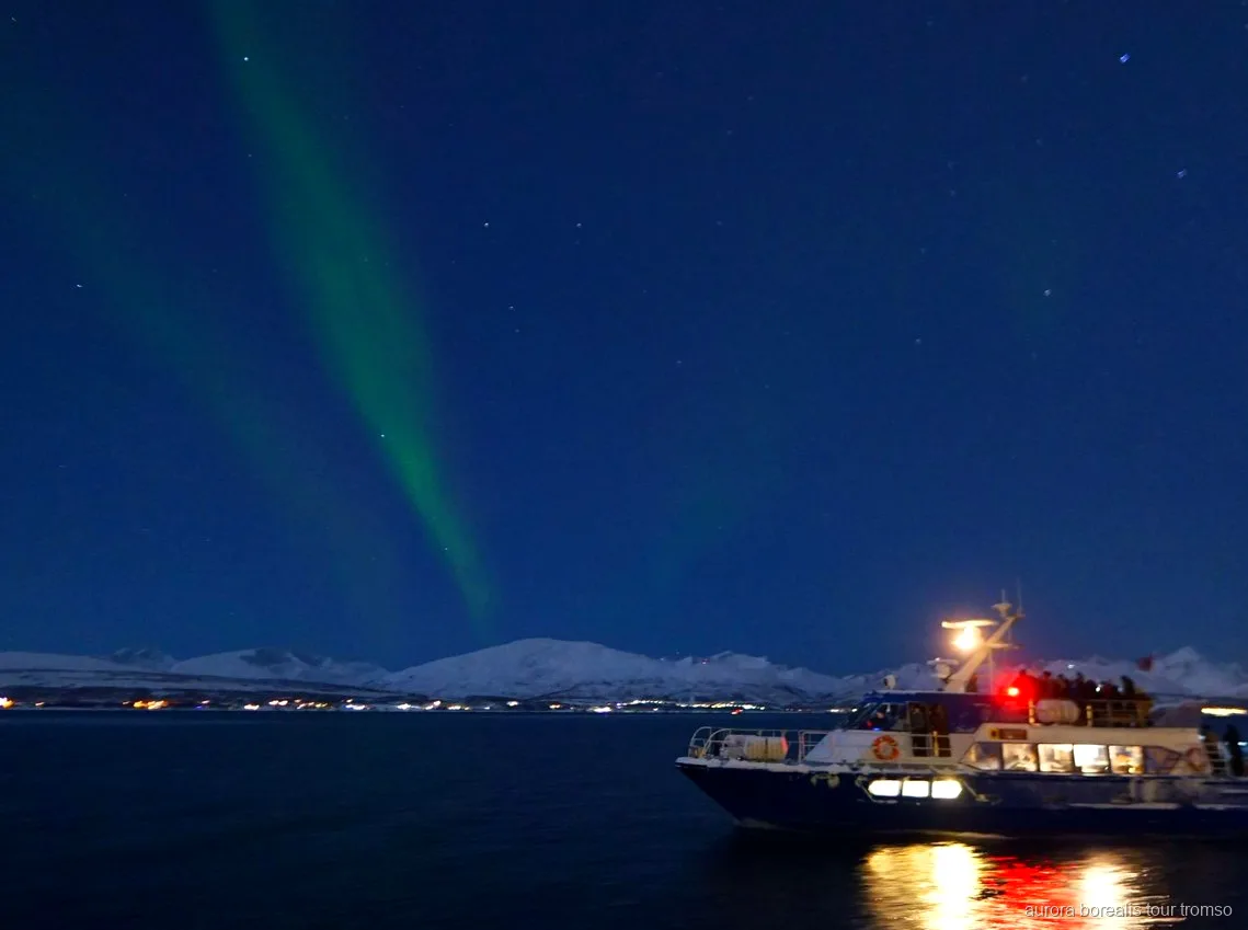 Norrsken över fjorden sett från Tromsø norrskenskryssningens båt